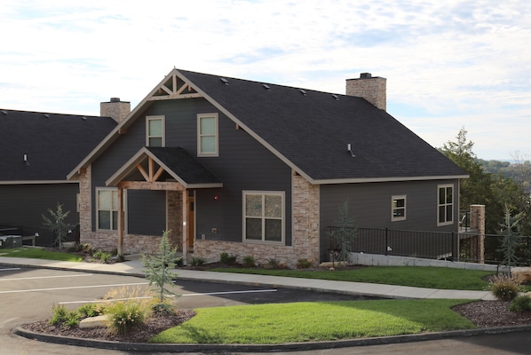 A modern two-story house with a stone facade, a dark roof, and a well-maintained lawn. - Antlers Resort (Branson)