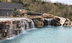 A swimming pool with a waterfall feature and a stone structure. - Antlers Resort (Branson)