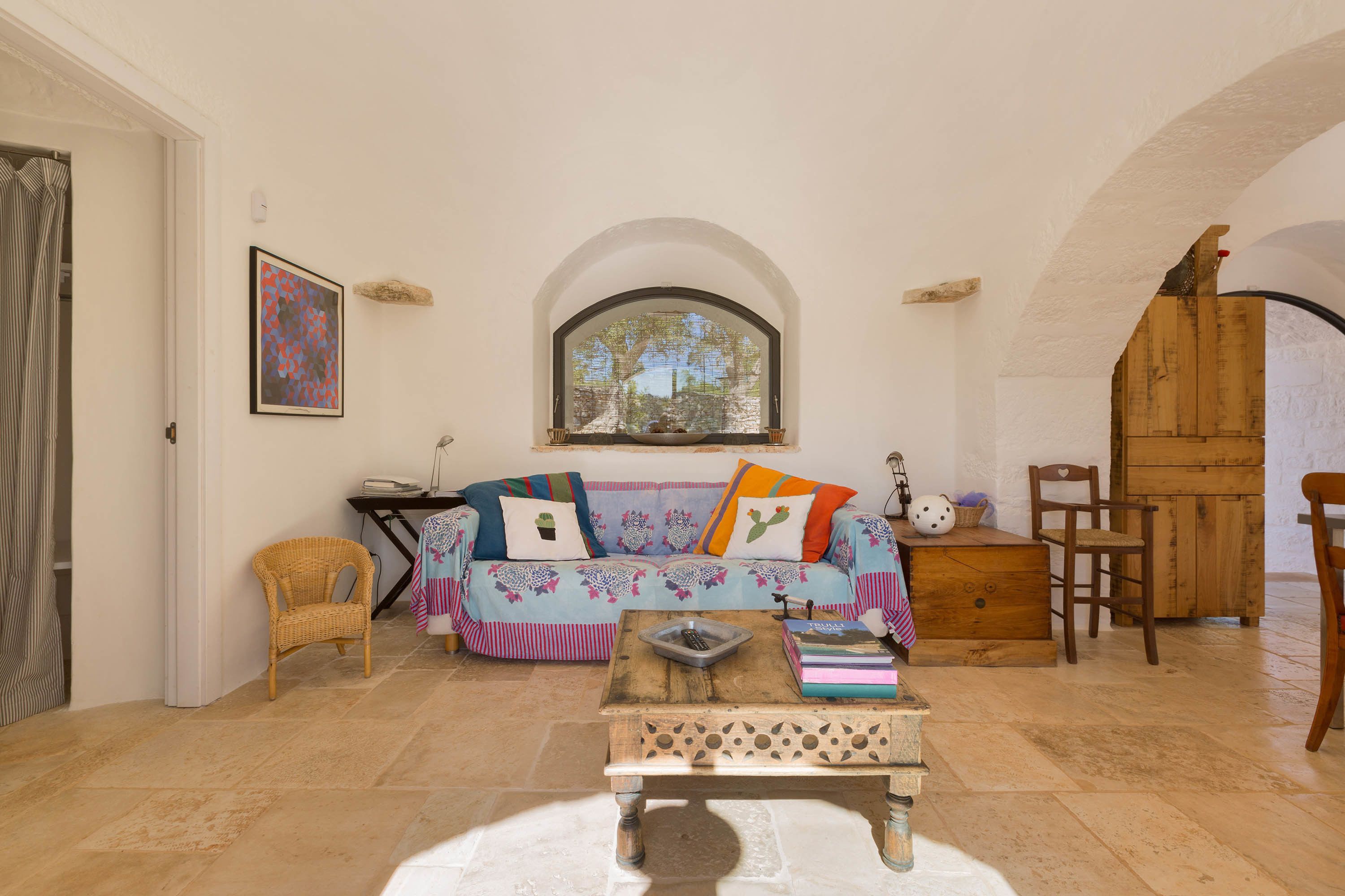 A cozy living room with a sofa, wooden coffee table, and a large arched window.