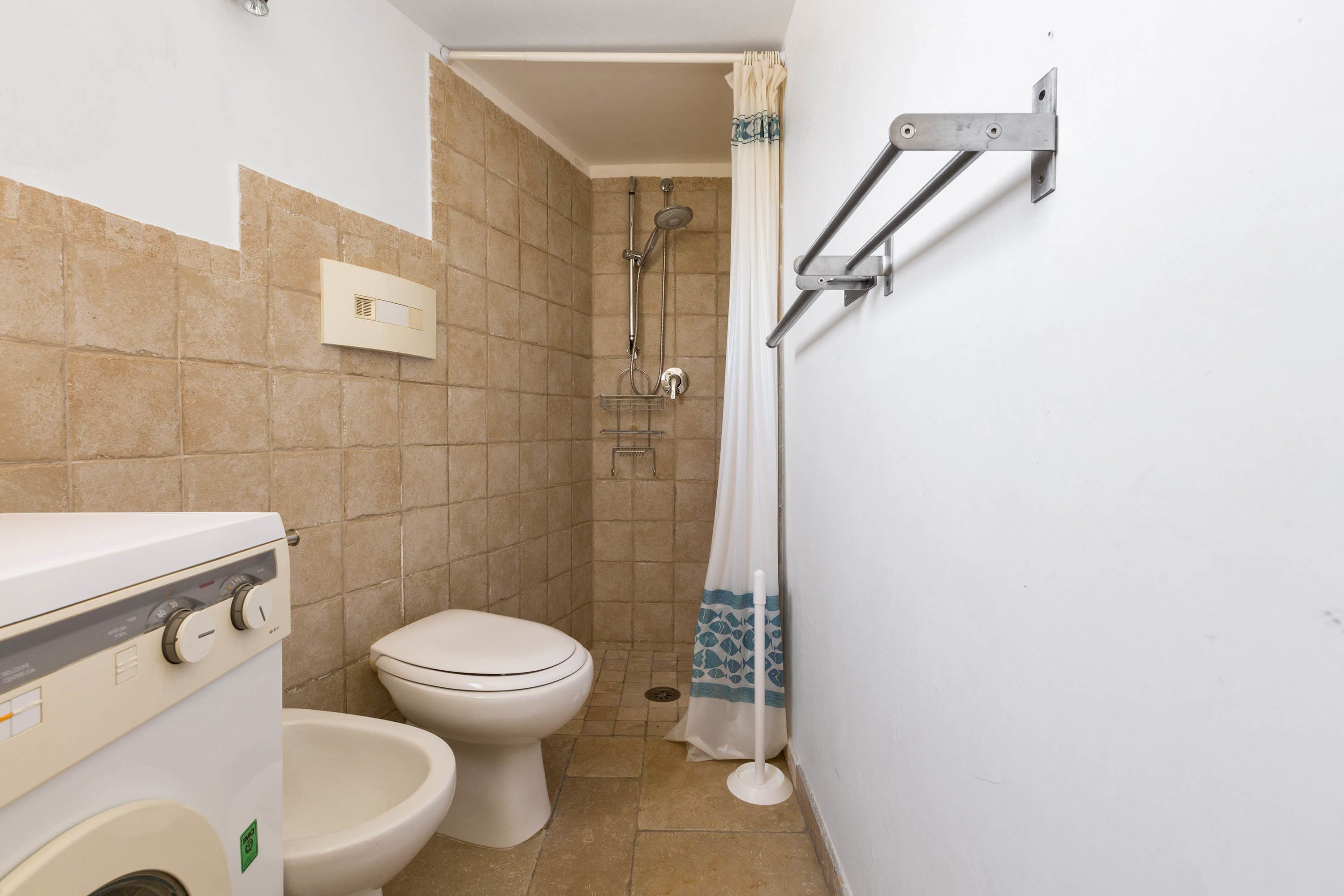A small bathroom with a toilet, a shower, and a washing machine.