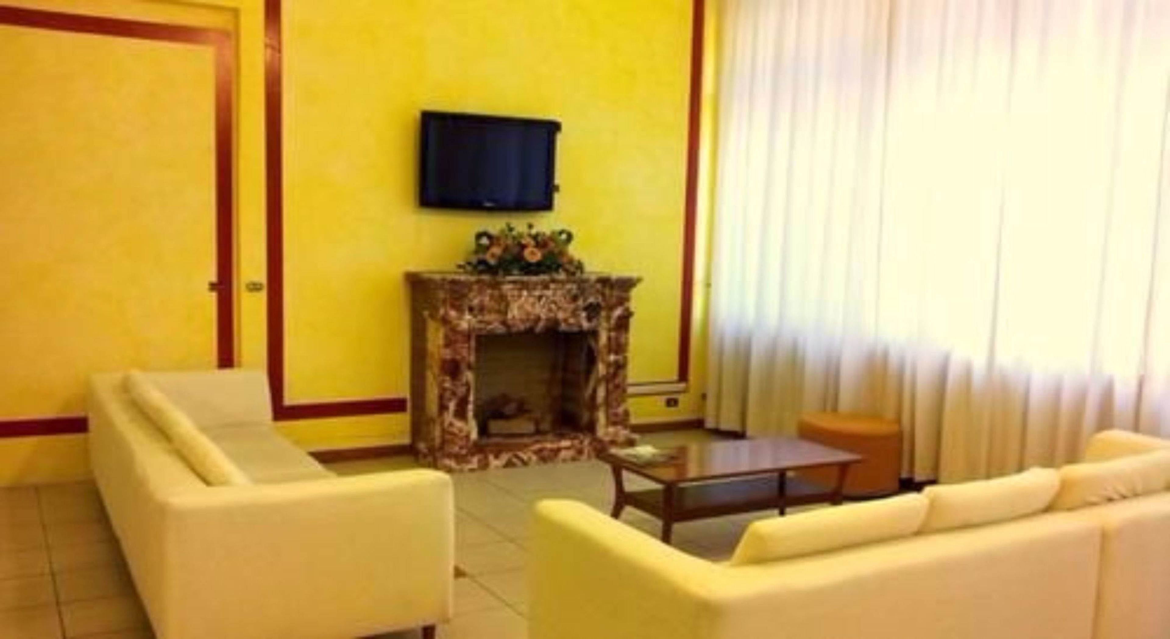 Un soggiorno con camino, una TV a schermo piatto montata a parete e una parete gialla.