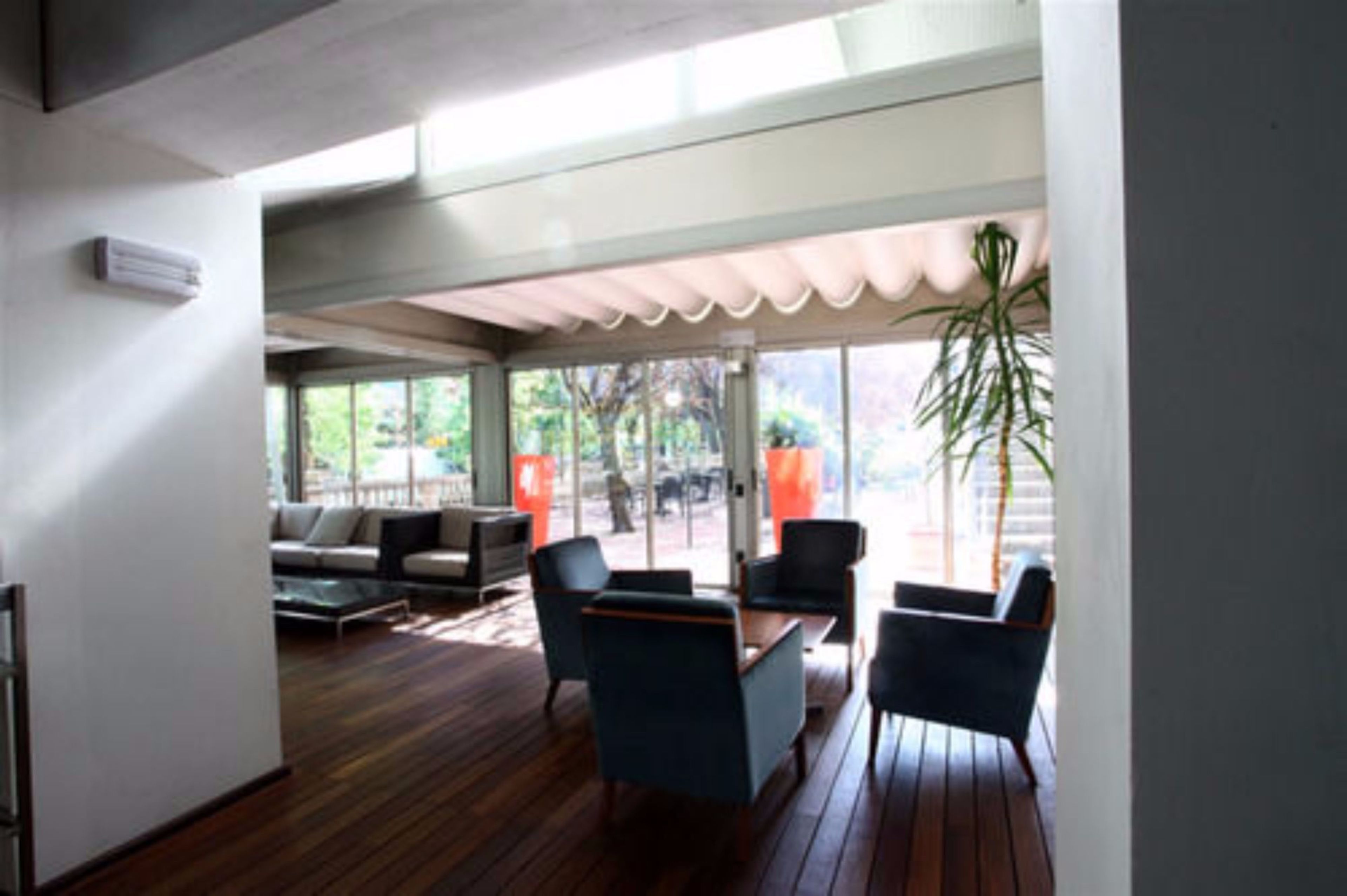 Un patio interior moderno con suelo de madera, un sofá y dos sillones.