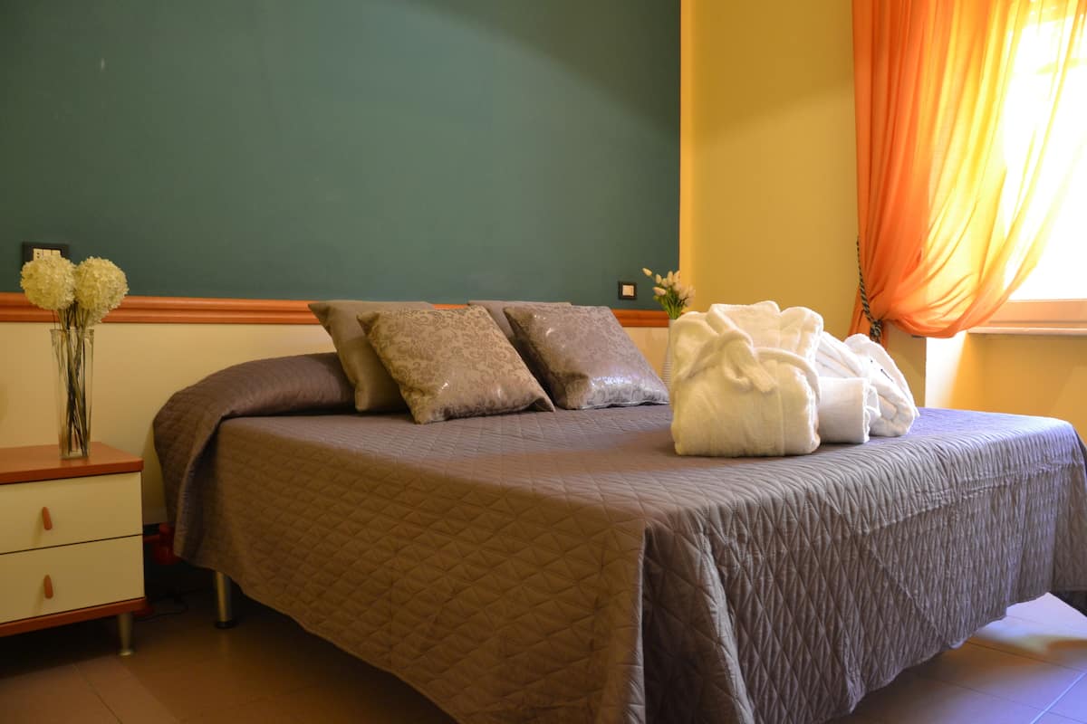 Una cama bien hecha con un cubrecolcha acolchado, dos almohadas decorativas y una toalla blanca encima.