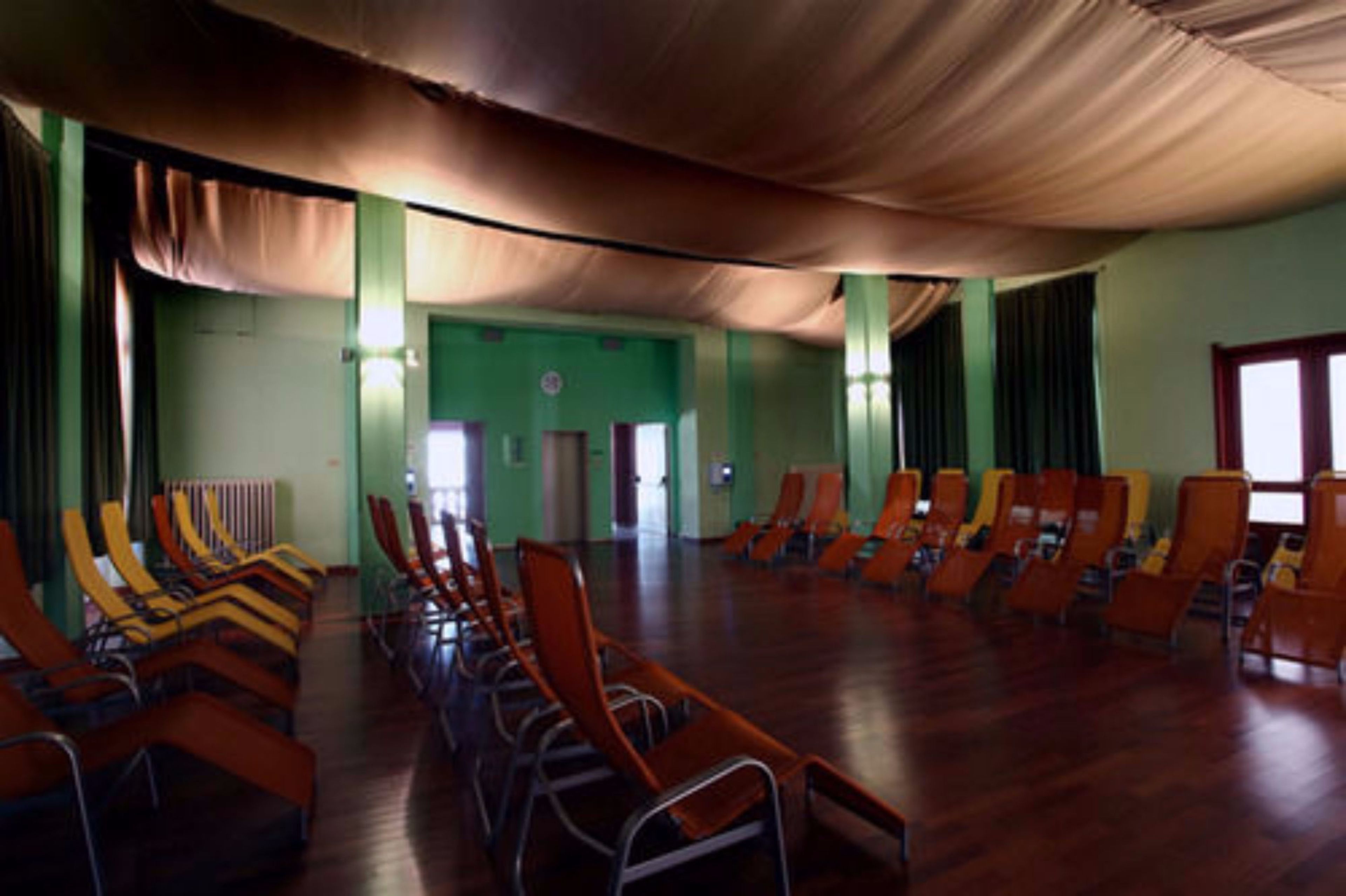 Un salón amplio con filas de sillas y un techo alto.