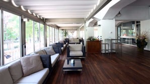 Ein modernes Interieur mit einer langen Sitzgruppe, Holzböden und großen Fenstern.