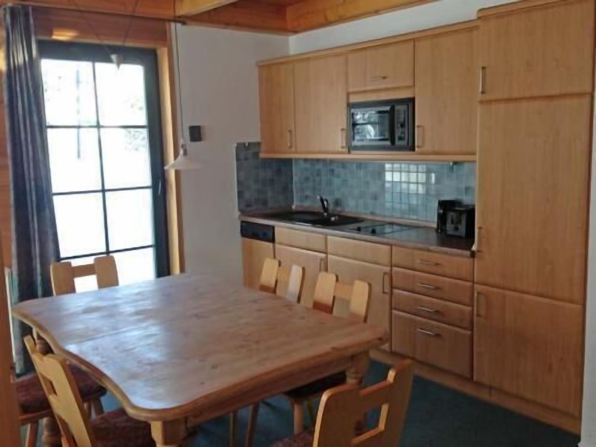 Cocina compacta con armarios de madera, microondas y fregadero.