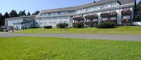 A hotel with a large, multi-story building, a covered outdoor area, and a well-maintained lawn.