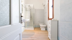 A modern bathroom with a glass shower enclosure, a toilet, and a white cabinet.