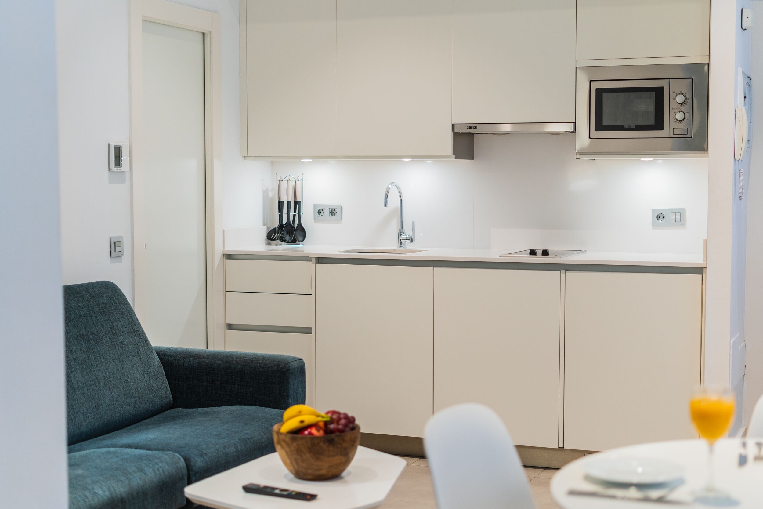 Cocina moderna con microondas, lavabo y un bol de fruta en la encimera.