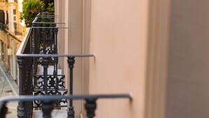 Un balcon orné de balustrades noires et sur lequel est posée une plante en pot.