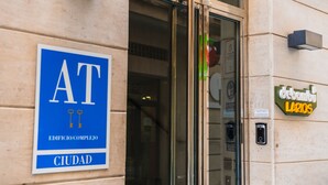 Une entrée d’immeuble avec une enseigne indiquant « AT CIUDAD » et une autre pour « debambou Larios ».
