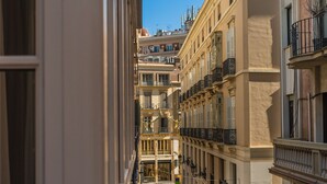 Une rue étroite bordée d’immeubles dotés de balcons et de fenêtres.