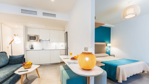 Une chambre d’hôtel moderne équipée d’une kitchenette, d’un canapé, d’une table à manger et d’un lit.