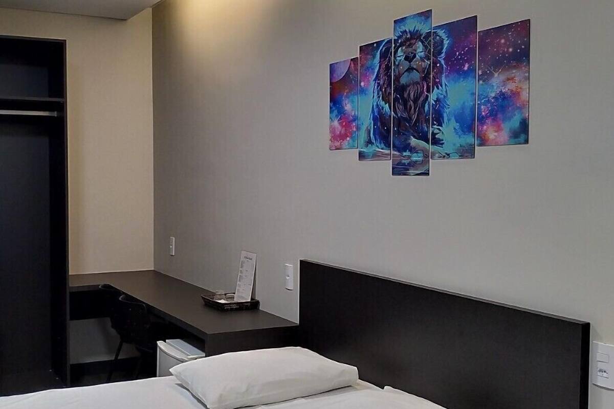 Una habitación de hotel moderna con una cama grande, un escritorio y una obra de arte colgada en la pared.
