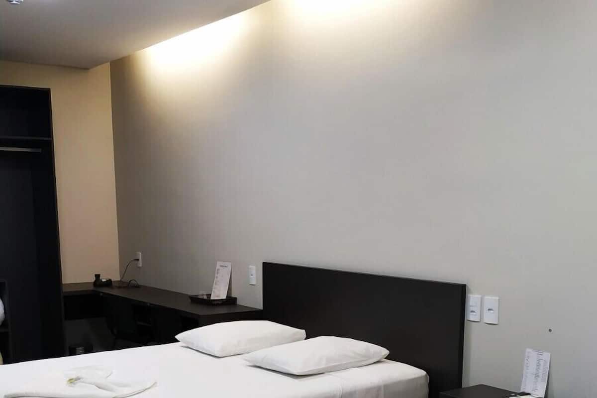 Habitación de hotel con dos camas, un escritorio y una silla.