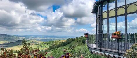 A balcony with a view of rolling hills and a clear sky.
