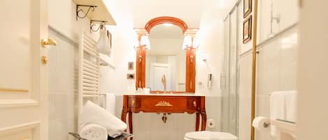 Een moderne badkamer met een witte betegelde vloer, een vrijstaand bad, een toilet en een wastafel met spiegel.