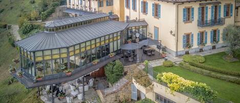 A large, two-story building with a glass conservatory and outdoor seating area.