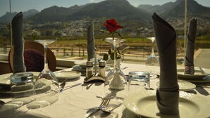 A table set for a meal with a rose and a glass vase, overlooking a mountainous landscape. - Prestige Hotel (Tetouan)