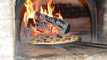 Pizza in een houtgestookte oven met vlammen.