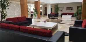 Un vestíbulo amplio con muebles modernos, incluyendo sofás y una mesa de centro, y plantas decorativas.