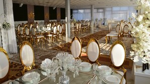 A banquet hall with round tables, gold chairs, and white floral arrangements. - Prestige Hotel (Tetouan)