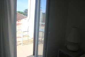 A room with a sliding glass door leading to an outdoor area with a tiled patio and a white chair. - Hotel La Settima Luna (Umag)