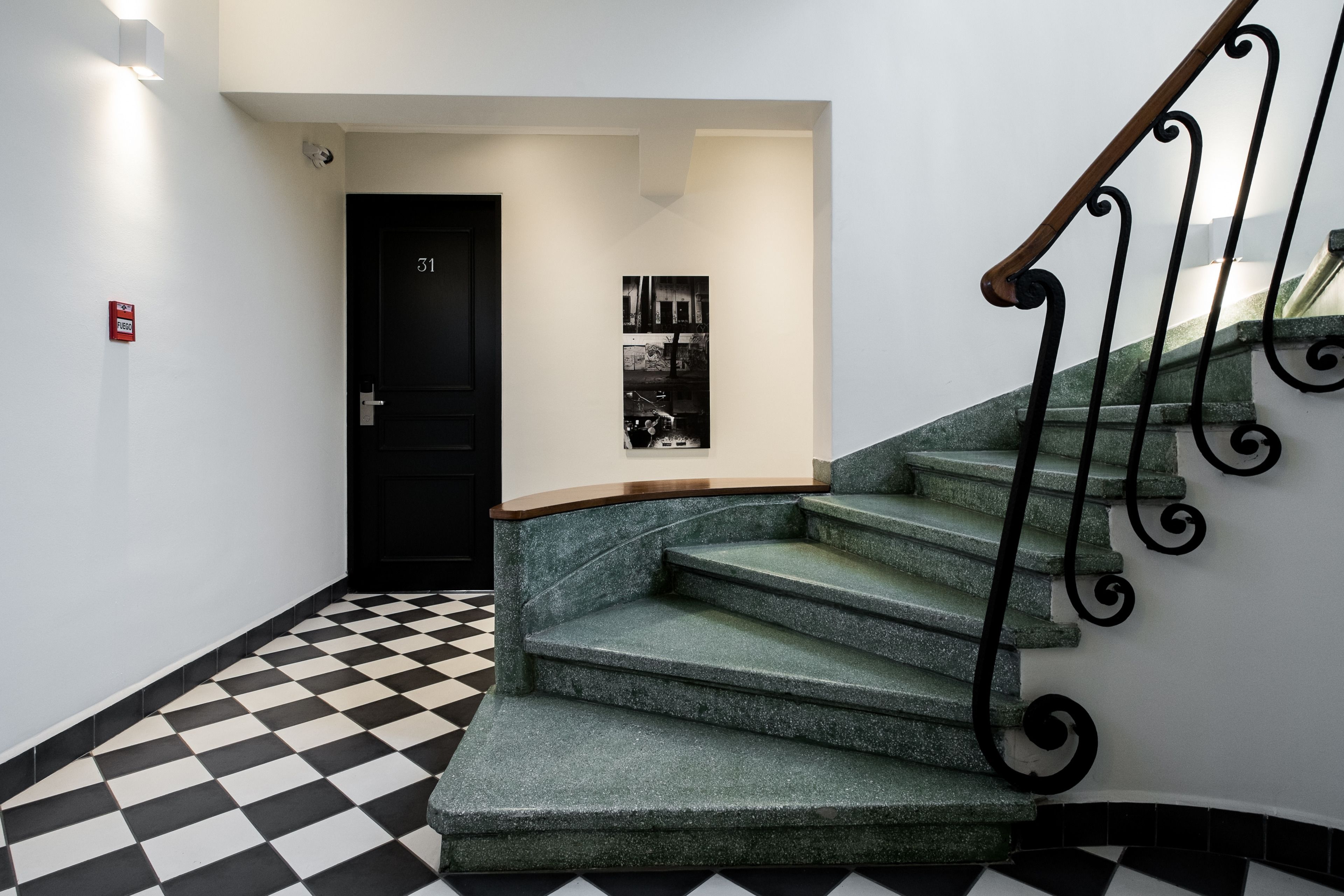 A staircase with a black and white checkered floor, a black door with the number 31, and a wall-mounted poster.