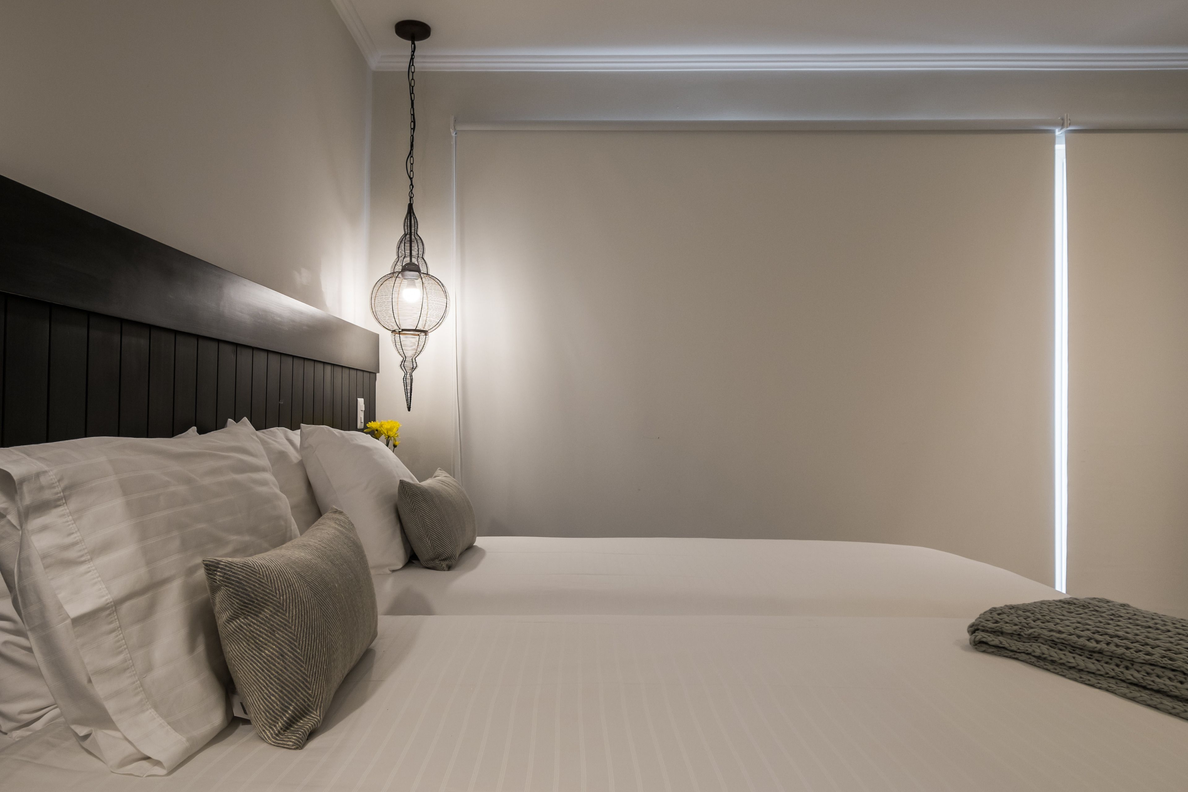 Un dormitorio moderno con una cama grande, una lámpara colgante y una mesita de noche con lámpara.