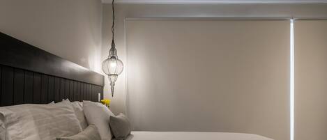 Un dormitorio moderno con una cama grande, una lámpara colgante y una mesita de noche con lámpara.