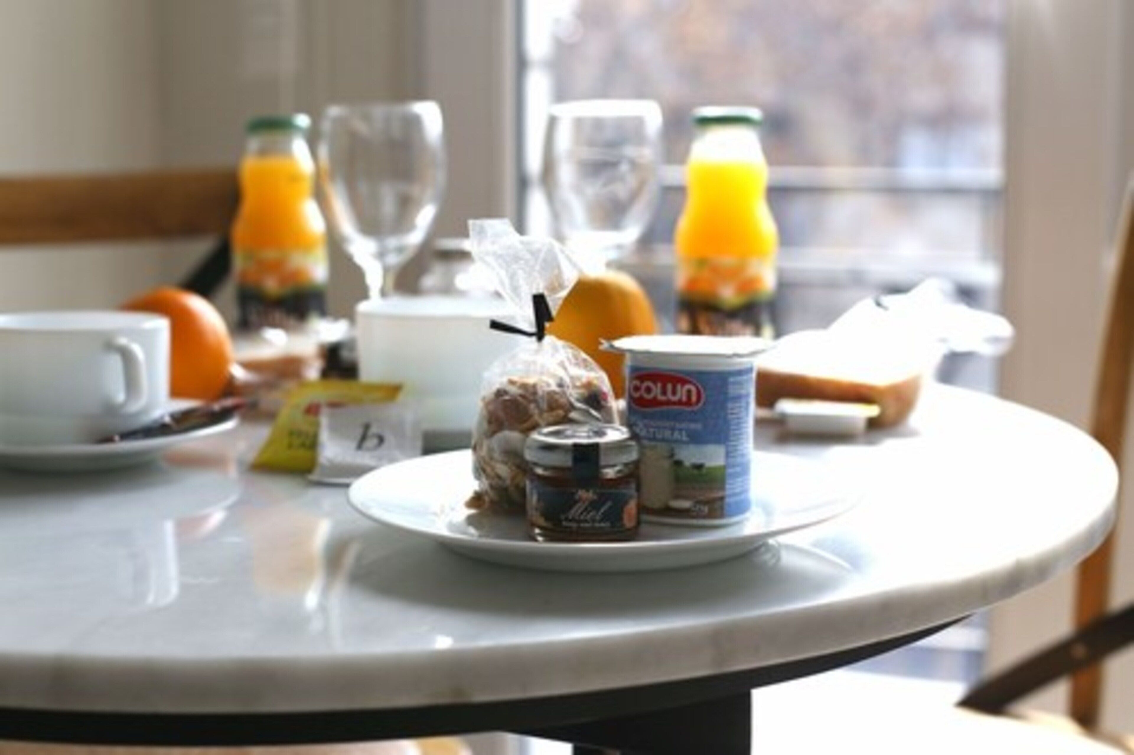 A breakfast table with a plate of food, a glass of orange juice, and a bottle of milk.