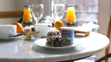 A breakfast table with a plate of food, a glass of orange juice, and a bottle of milk.