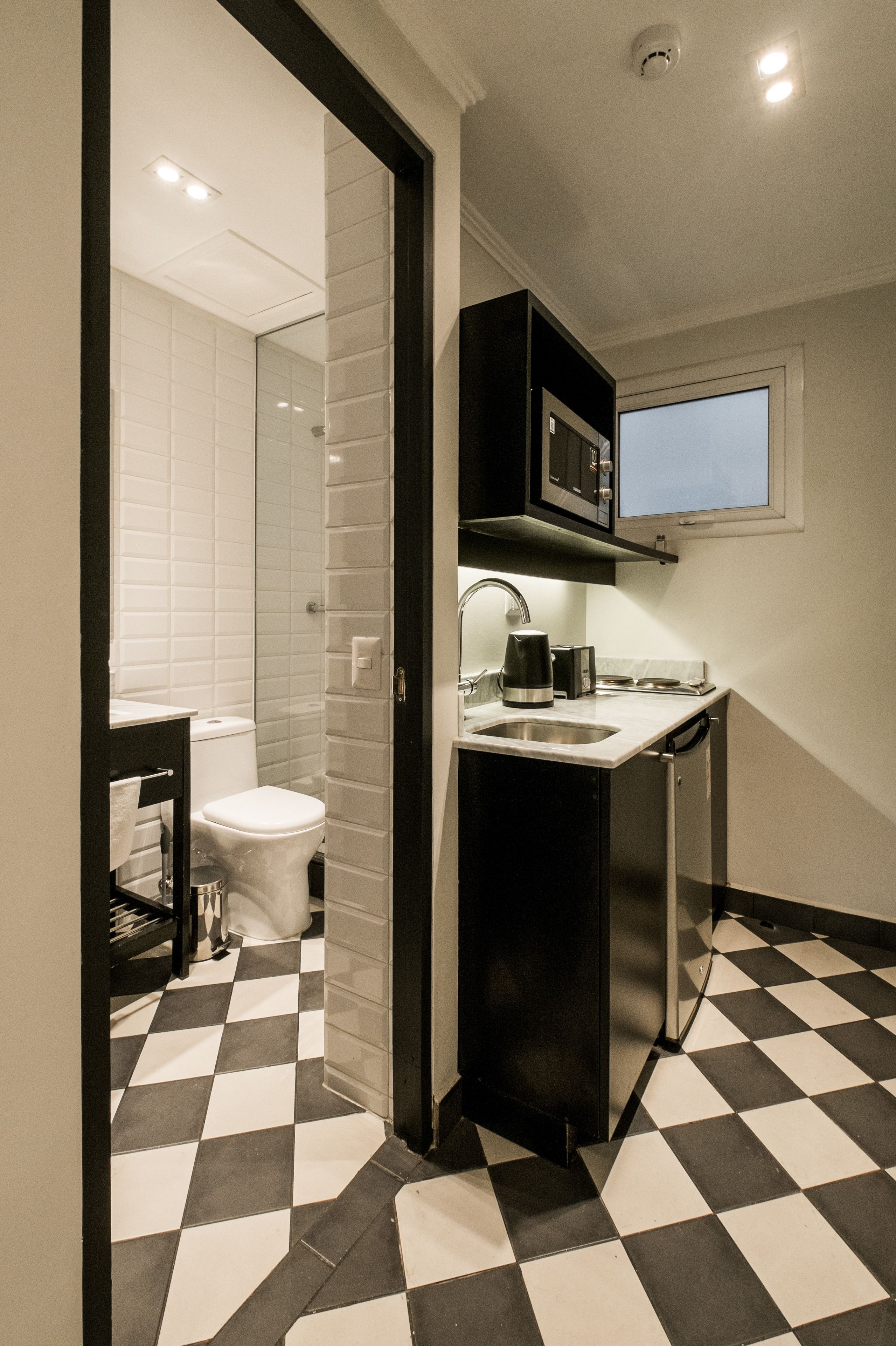 A compact kitchen with a sink, microwave, and a small window.