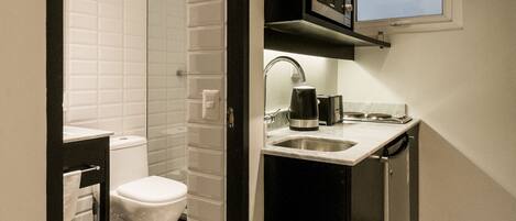 A compact kitchen with a sink, microwave, and a small window.