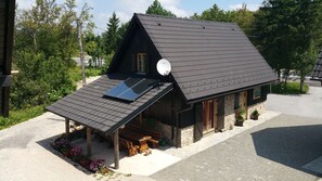 Eine Holzhütte mit geneigtem Dach, Solaranlagen und einem Steinfundament.
