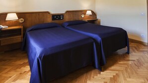 A hotel room with two beds, wooden headboards, bedside tables with lamps, and a control panel on the headboard. - Hotel Moderno (Pontassieve)