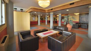 A lobby with leather seating, a chandelier, and potted plants. - Hotel Moderno (Pontassieve)
