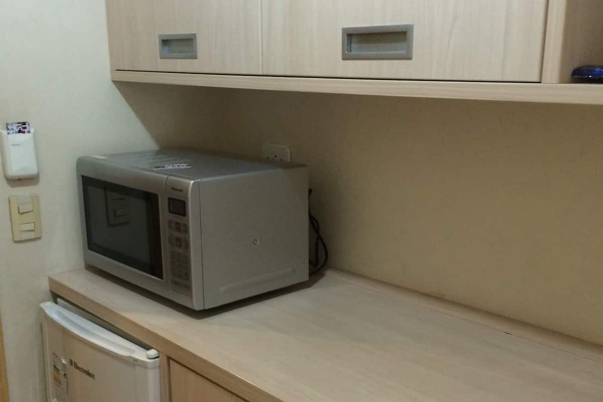 A kitchenette with a microwave, a small refrigerator, and wooden cabinets.