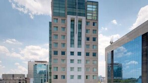 Un edifici modern i alt amb múltiples plantes, finestres grans i una façana de vidre destacada.