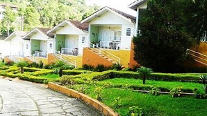 A row of small, single-story houses with individual balconies and a stone pathway leading to them. - Hotel H Santo Antonio do Pinhal (Monteiro Lobato)