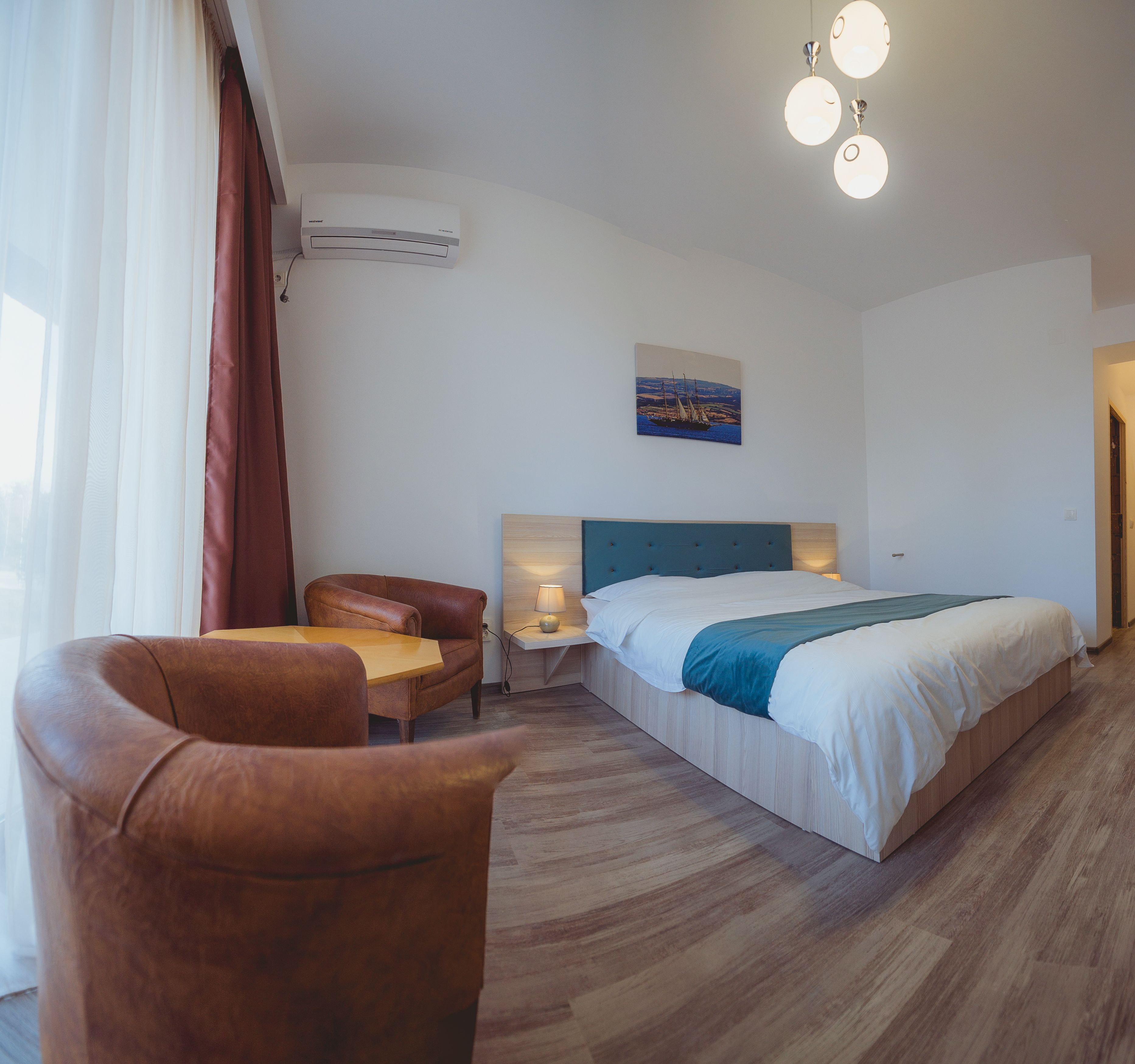 Habitación de hotel con cama, una silla, un escritorio y aire acondicionado instalado en la pared.