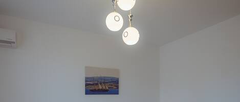 A bedroom with a bed, bedside lamps, a ceiling light fixture, and a wall-mounted painting.