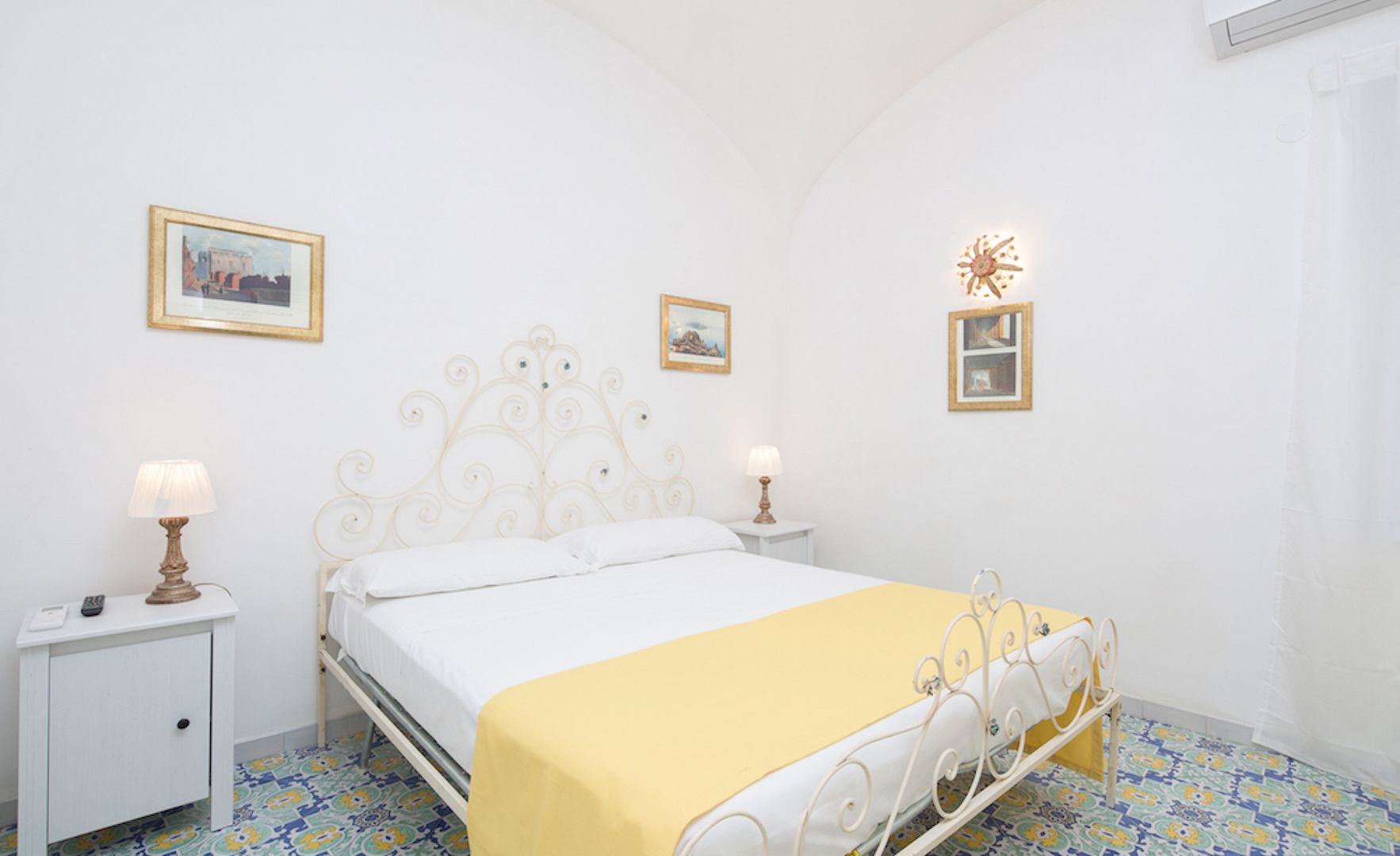 A bedroom with a bed, bedside tables, and wall-mounted lamps.