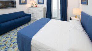 Una habitación de hotel con cama, sofá, cómoda y ventana con cortinas.