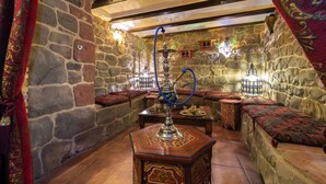 Una habitación tradicional con paredes de piedra, un narguilé y cojines decorativos.
