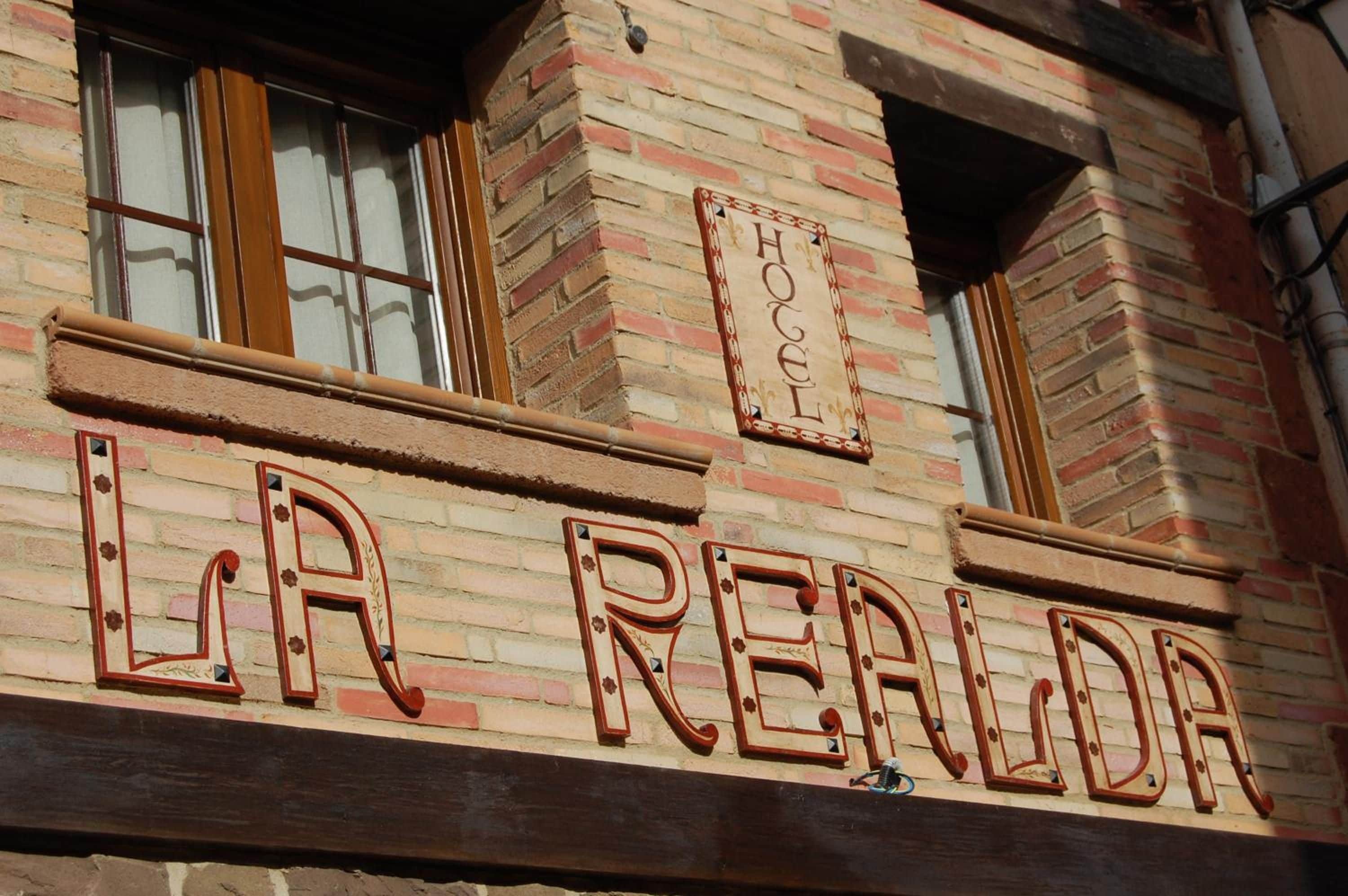Fachada de edificio con un letrero que dice 'LA REALDA' y un letrero más pequeño encima que dice 'HOTEL'.