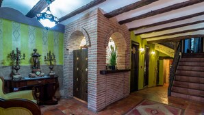 Un interior tradicional con vigas de madera a la vista, arcos de ladrillo y suelo de baldosas.