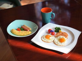 Una mesa con dos platos de comida: uno con tortilla y salchichas, y otro con huevos fritos y una hamburguesa.