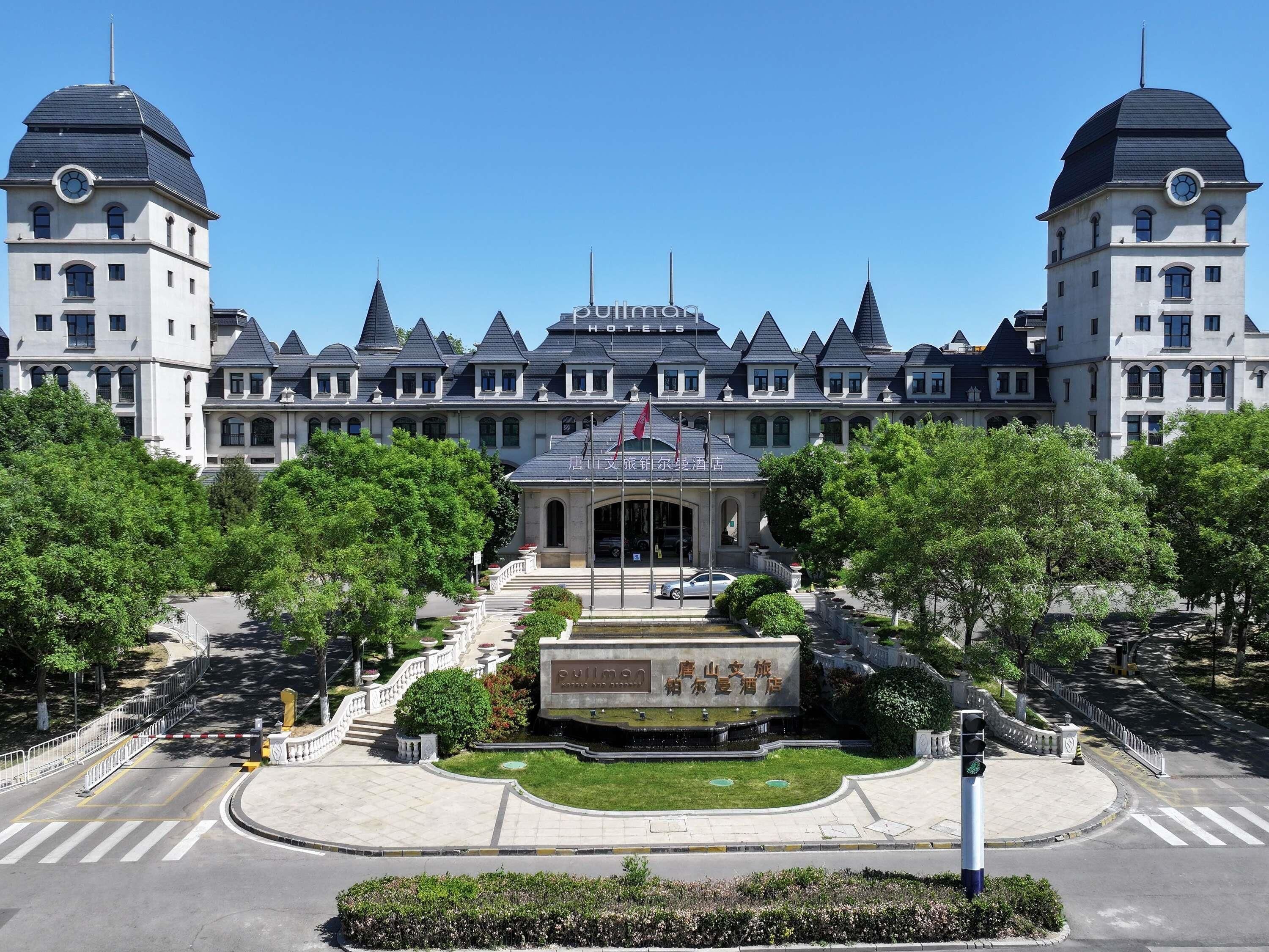 A large, historic building with a symmetrical facade, multiple towers, and a central entrance with steps leading up to it.