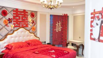 Un dormitorio con una cama grande, una araña y elementos decorativos, incluyendo una pared roja con caracteres chinos y una cortina roja con caracteres chinos.